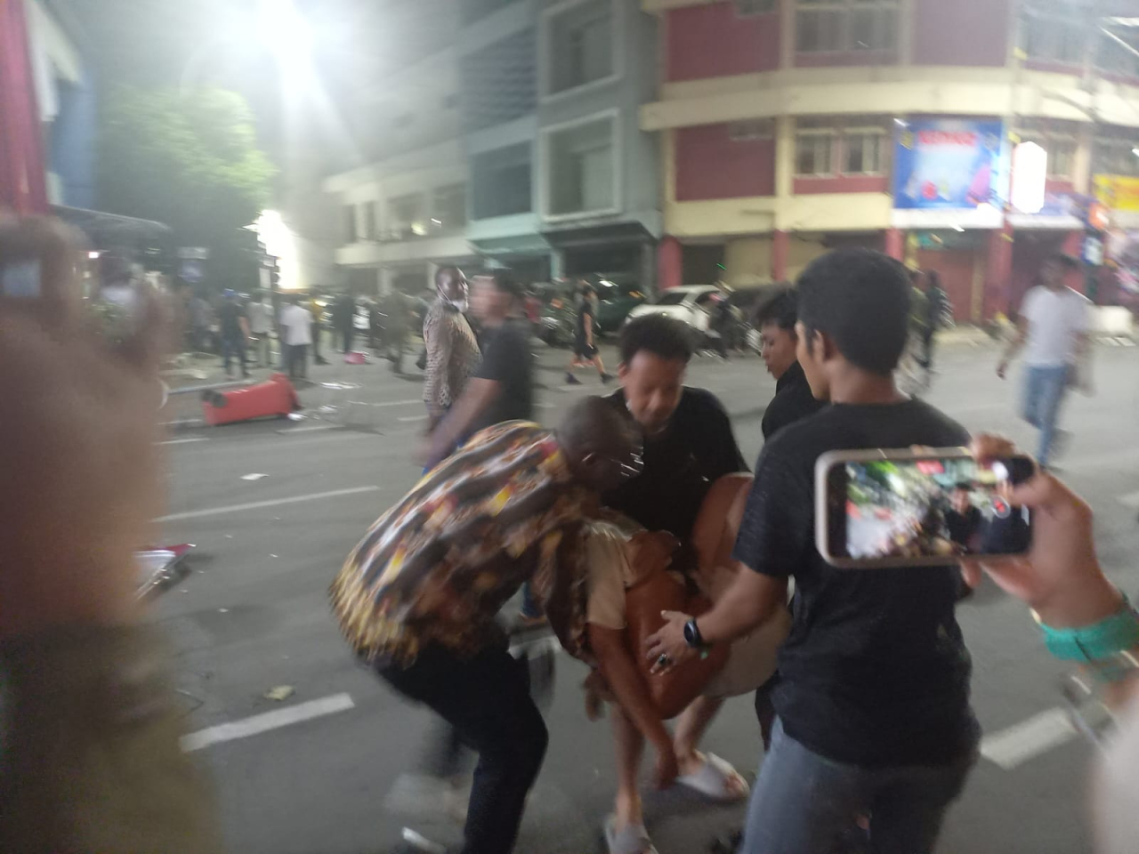 Salah satu orang dibopong saat kericuhan di Pentas Seni dan Budaya Papua di Kya-Kya Surabaya, Minggu (27/7/2025). (Foto: Trisna Eka Aditya/Lingkaran.net)